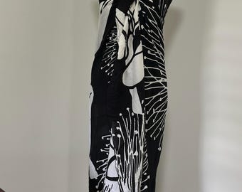 Peut inclure: Un paréo noir et blanc avec un motif botanique. Le paréo est enroulé autour d'un mannequin, mettant en valeur son tissu fluide et son motif abstrait. Le motif présente des formes et des lignes organiques blanches sur fond noir.