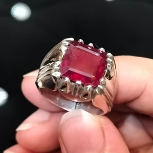 May include: A silver ring with a large, red, rectangular gemstone.