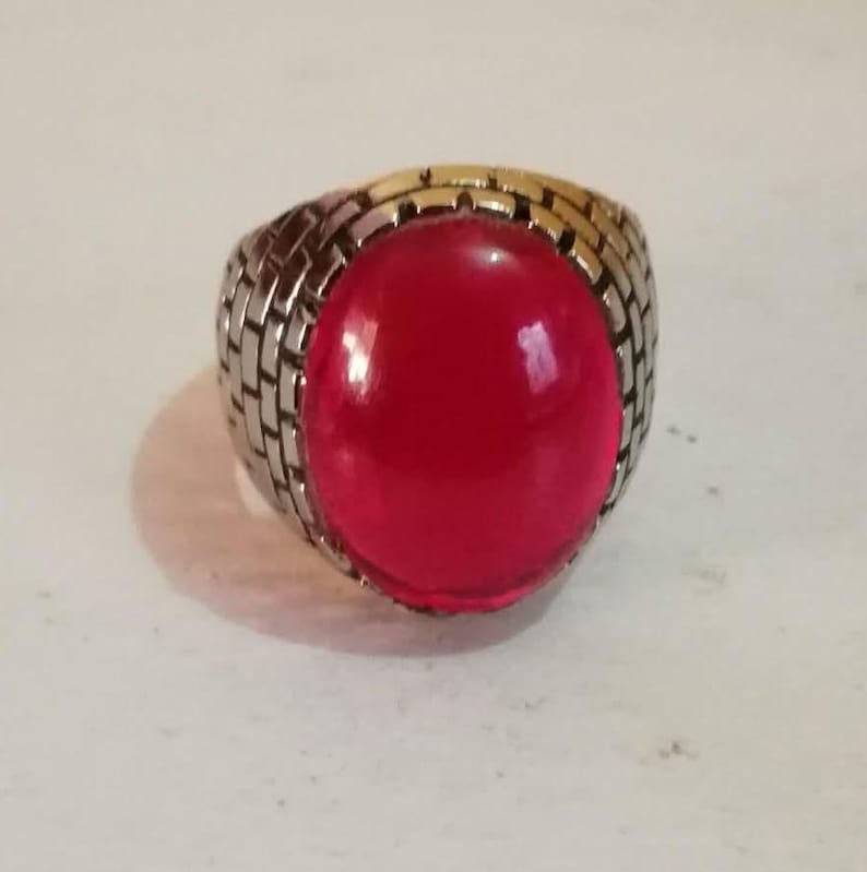Puede incluir: Un anillo de plata con una piedra preciosa roja brillante de gran tama&ntilde;o. El anillo tiene una banda texturizada.