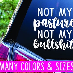 May include: White vinyl decal with the text "Not my pasture, not my bullshit" on a blue car window. The text is in a cursive font. The decal is available in many colors and sizes.