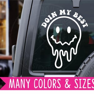 May include: White vinyl decal of a melting smiley face with the text "Doin My Best" around it. The decal is on the back window of a car.