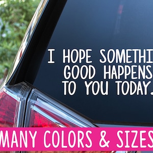 May include: A black car with a white vinyl decal on the back window that reads "I hope something good happens to you today." The decal is on a black car with a red taillight. The text "MANY COLORS & SIZES" is printed in white on a pink banner at the bottom of the image.