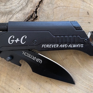May include: Black multi-tool with a black blade, a bottle opener, and a seatbelt cutter. The tool is engraved with "G+C FOREVER AND ALWAYS".