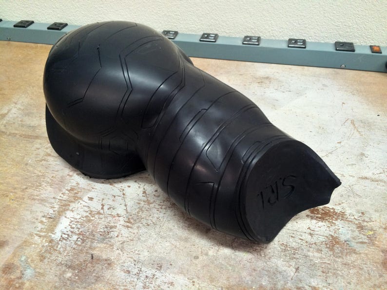 May include: Black rubber mold of a human arm, with a textured surface and the letters "J.S." on the back.