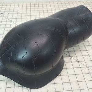 May include: Black rubber elbow pad with a textured surface and a geometric pattern.