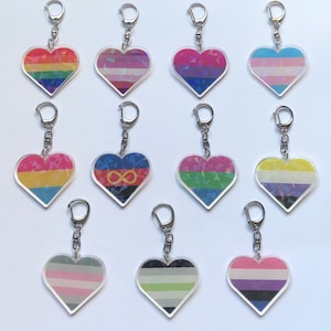 Peut inclure: Douze porte-clés en forme de cœur avec différents motifs de drapeaux arc-en-ciel. Les porte-clés sont en acrylique transparent avec une finition holographique. Les drapeaux incluent les drapeaux arc-en-ciel, transgenre, bisexuel, pansexuel, genderqueer, lesbien, non-binaire et asexuel.