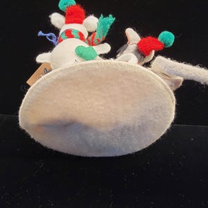 Puede incluir: Dos adornos de mu&ntilde;eco de nieve con detalles en rojo, verde y blanco. Cada mu&ntilde;eco de nieve tiene un gorro rojo con un pomp&oacute;n verde y una bufanda a juego. Los adornos est&aacute;n sobre una base ovalada de color claro.