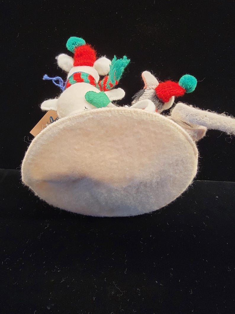 Puede incluir: Dos adornos de mu&ntilde;eco de nieve con detalles en rojo, verde y blanco. Cada mu&ntilde;eco de nieve tiene un gorro rojo con un pomp&oacute;n verde y una bufanda a juego. Los adornos est&aacute;n sobre una base ovalada de color claro.