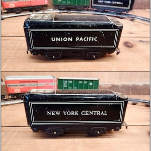 Könnte beinhalten: Zwei antike Spielzeug-Waggons, einer schwarz mit dem Aufdruck "UNION PACIFIC" und der andere schwarz mit dem Aufdruck "NEW YORK CENTRAL". Beide Waggons haben silberne Akzente und stehen auf einer Holzoberfläche.