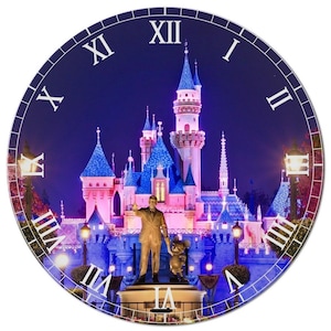 May include: A round clock with a blue background featuring a pink and blue castle with lights. The clock face has Roman numerals and a white background. The castle is surrounded by trees and lights. Walt Disney and Mickey Mouse stand in front of the castle.