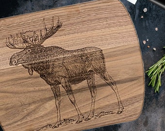 May include: A wooden cutting board with a carved image of a moose. The board is brown and has a natural wood grain.