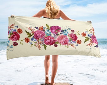 May include: A beach towel with a floral design featuring pink, red, and blue flowers on a cream background.