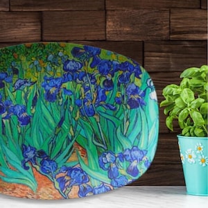 Può includere: Un piatto da portata ovale in ceramica con un vivace design floreale blu e verde. Il design presenta una rappresentazione stilizzata di iris, un soggetto popolare nell'arte.