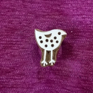 May include: White wooden block stamp shaped like a bird with a dotted pattern. The bird has two legs and feet.