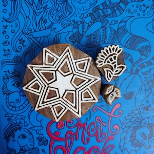 May include: Three wooden printing blocks with intricate designs. The largest block features a starburst pattern, while the other two blocks depict a flower and a leaf.