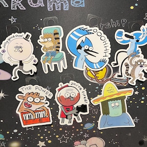 May include: A collection of cartoon character stickers. The stickers feature characters in various poses, with some including text like "jolly good show!" and "THE POWER". The stickers are colorful and have a glossy finish.