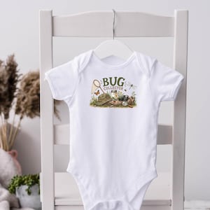 May include: A white short-sleeved bodysuit featuring a graphic print with the text "BUG COLLECTOR" in green letters. The illustration includes a tan hat, a butterfly net, a magnifying glass, a jar, a butterfly, and a dragonfly on green grass.