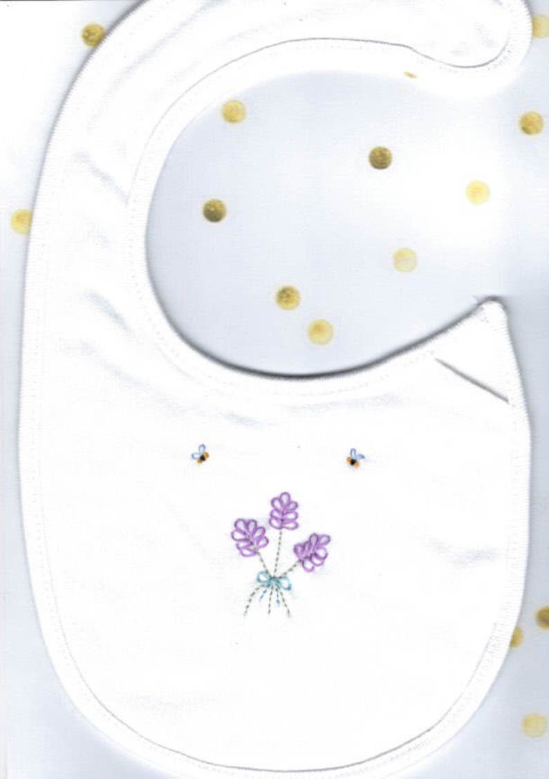 May include: White cotton baby bib with embroidered purple flowers and two bees.