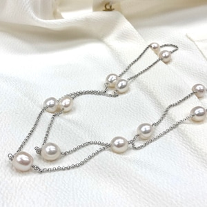 Op de afbeelding: Een zilveren ketting met witte parels. De ketting is dubbelstrengs en heeft in totaal acht parels.