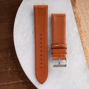 Pu&ograve; includere: Due cinturini per orologio in pelle marrone con dettagli di cucitura. Un cinturino ha una fibbia.