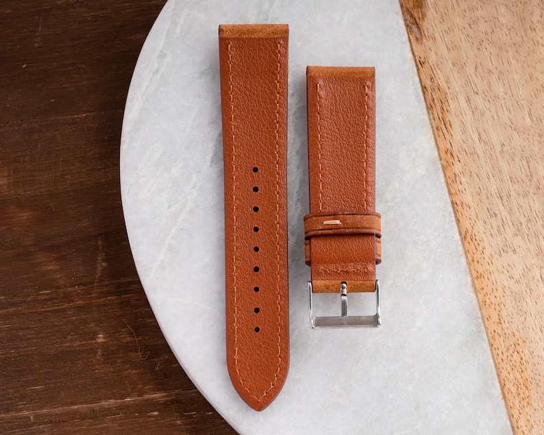 Pu&ograve; includere: Due cinturini per orologio in pelle marrone con dettagli di cucitura. Un cinturino ha una fibbia.