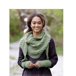 Könnte beinhalten: Eine Frau trägt einen grünen Strick-Schal und passende fingerlose Handschuhe. Der Schal hat ein strukturiertes Muster und ist um ihren Hals gelegt. Die Handschuhe sind in einer einfachen Rippenstruktur gestrickt. Die Frau lächelt und schaut in die Kamera. Das Bild enthält den Text "DROPS DESIGN. www.garnstudio.com".