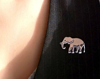 Könnte beinhalten: Eine schwarze Weste mit Nadelstreifen und einer silbernen Elefanten-Anstecknadel.