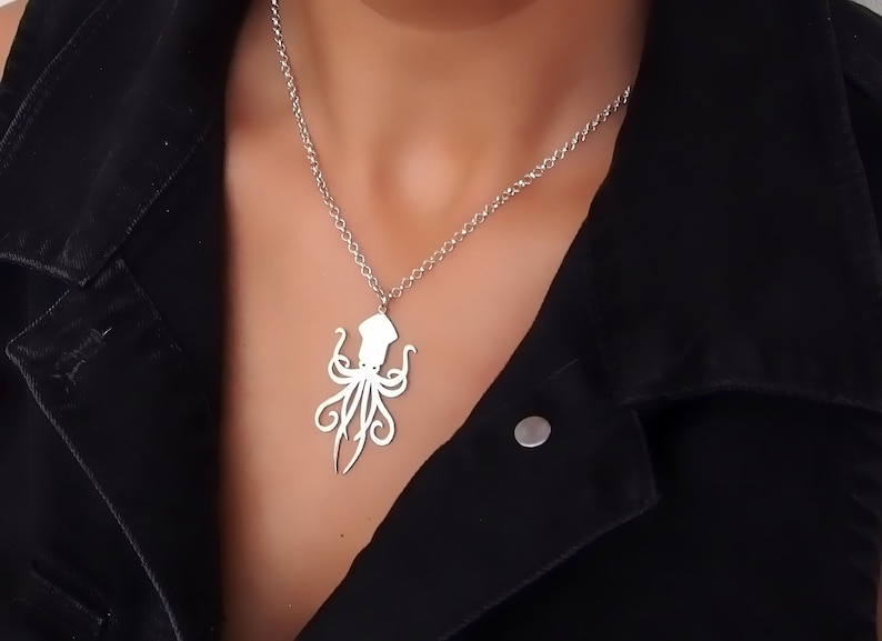 May include: A silver necklace with a detailed octopus pendant. The necklace is worn by a person with a black jacket.