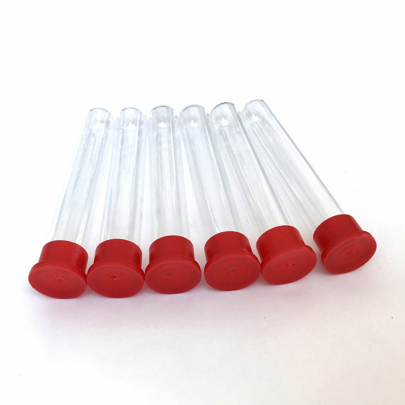 May include: Six clear plastic test tubes with red caps are arranged on a white surface. The tubes are cylindrical and angled slightly. The red caps are flat and circular, providing a contrasting color to the transparent tubes.