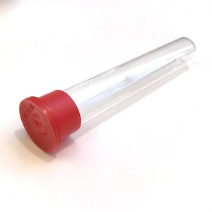 May include: A clear glass tube with a red cap. The tube is cylindrical and appears to be empty. The red cap is on the left side of the tube and has some text on it. The background is white.