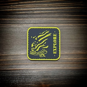 Peut inclure: Un écusson brodé noir et jaune avec un motif d'aigle et le texte "Born Adventure - Explore".