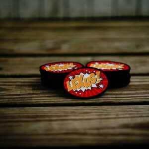 May include: Three red and black round patches with a white and yellow comic book style graphic that says "LEXUS!"