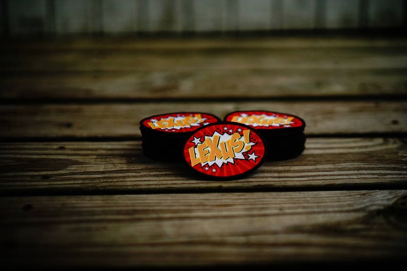 May include: Three red and black round patches with a white and yellow comic book style graphic that says "LEXUS!"