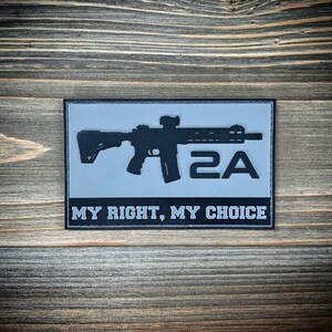 May include: A grey and black patch with a silhouette of a rifle and the text "2A MY RIGHT, MY CHOICE".