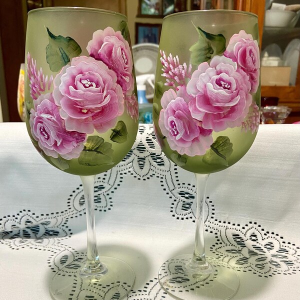 Un juego de copas de vino esmeriladas verdes pintadas a mano con suaves rosas rosadas.