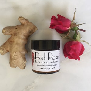 May include: A small jar of organic joint salve with a white label that reads "Red Rose Lotions & Potions organic healing botanicals JOINT SALVE". The jar is surrounded by a ginger root and two red roses.