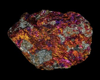 May include: A raw mineral specimen featuring a rough, crystalline texture with a vibrant iridescent surface. The stone displays a complex mix of metallic gold, deep copper, bright magenta, and silver-grey tones across its jagged, uneven form.