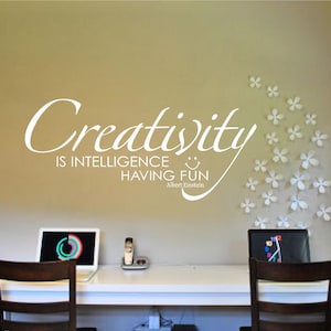 May include: White wall decal with the quote "Creativity is intelligence having fun - Albert Einstein". The quote is surrounded by white paper flower cutouts.