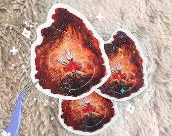 May include: Three die-cut stickers featuring a character in a red dress and a white mask, set against a fiery, detailed background. The stickers are held by tweezers, showcasing the artwork's vibrant colors and intricate design.