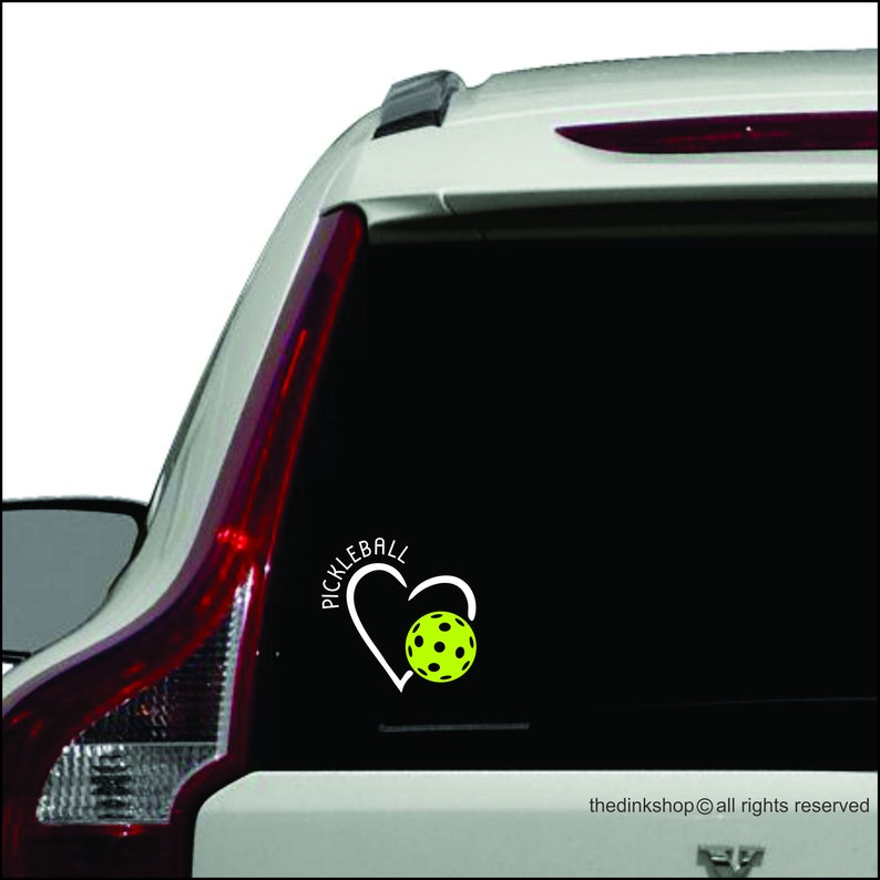 May include: White vinyl decal with a heart shape and the word "Pickleball" inside the heart. A yellow pickleball is inside the heart.