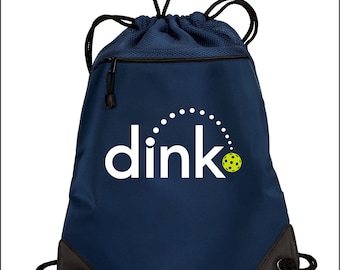 May include: A navy blue drawstring bag with a white logo that says "dink" and a yellow and white pickleball. The bag has a zippered pocket on the front.