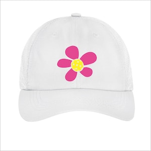 May include: White mesh baseball cap with a pink flower design. The flower has a yellow center with white polka dots.