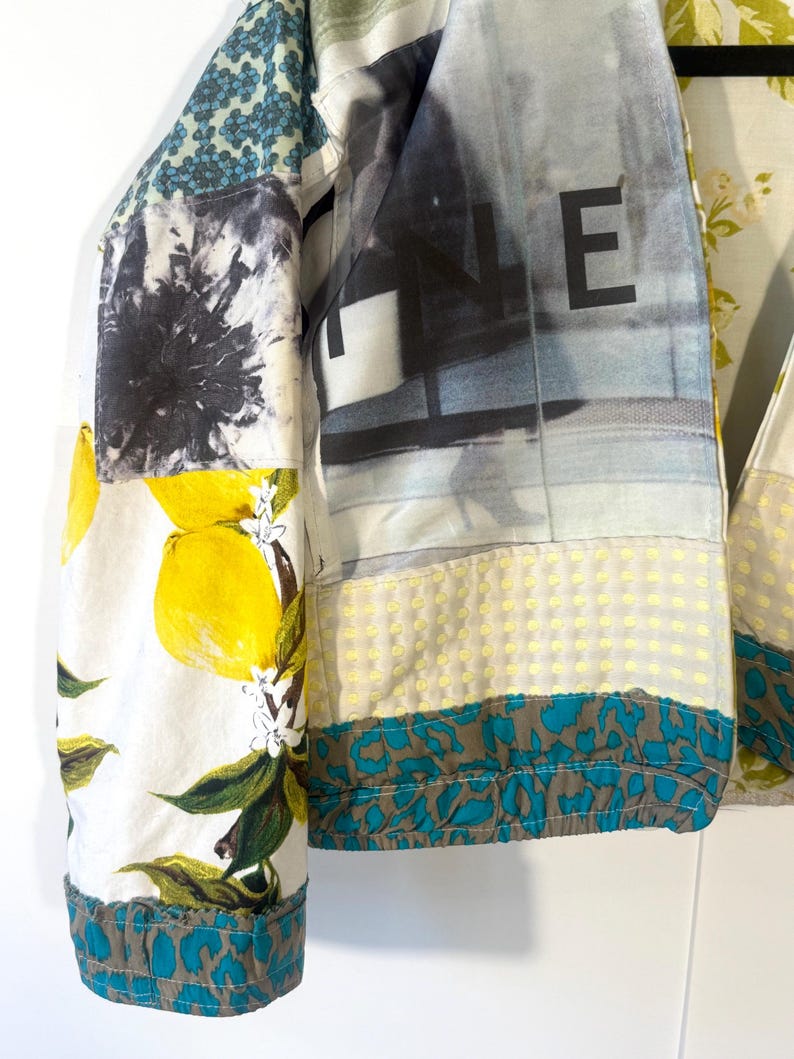 Pode incluir: Uma jaqueta patchwork com v&aacute;rios padr&otilde;es e estampas. A jaqueta apresenta uma estampa de lim&atilde;o, uma estampa de paisagem urbana com a letra "E" e outros desenhos abstratos. As mangas t&ecirc;m uma borda com estampa de leopardo em azul-petr&oacute;leo e marrom.