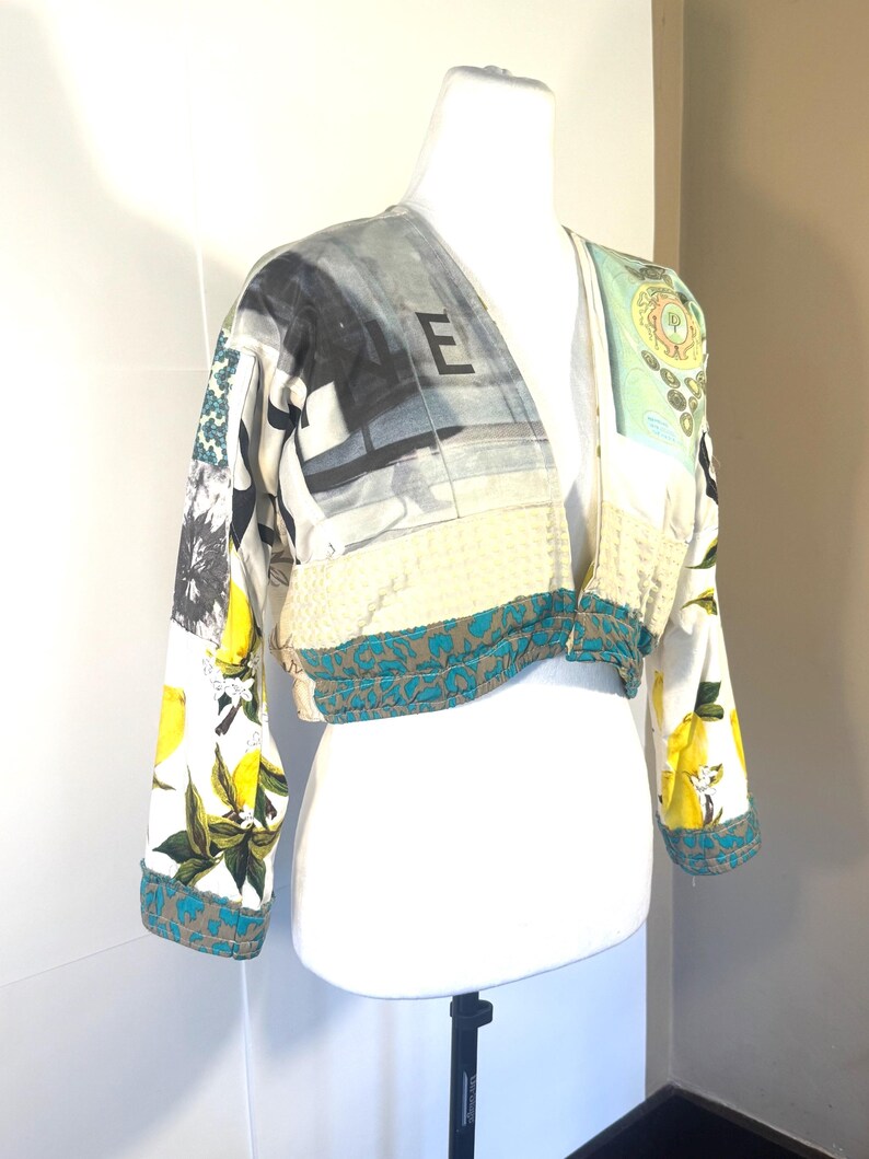 Pode incluir: Casaco curto com decote em V em um manequim. O casaco apresenta um design de patchwork com lim&otilde;es, estampas florais e desenhos abstratos. As mangas e a bainha s&atilde;o aparadas com um tecido estampado em azul-petr&oacute;leo e marrom. A letra "E" &eacute; vis&iacute;vel no casaco.