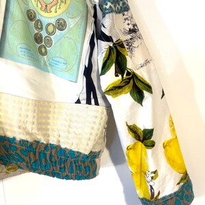 Pode incluir: Uma jaqueta patchwork com v&aacute;rios padr&otilde;es e estampas. A jaqueta apresenta uma base branca com estampas de lim&otilde;es e folhas nas mangas e uma se&ccedil;&atilde;o com um gr&aacute;fico de estilo vintage. A bainha tem uma estampa de animal em verde-azulado e marrom.