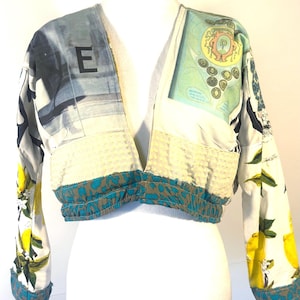 Pode incluir: Casaco curto com um design patchwork &uacute;nico. O casaco apresenta uma mistura de padr&otilde;es, incluindo lim&otilde;es, mapas e estampas abstratas. As mangas t&ecirc;m uma estampa de lim&atilde;o, enquanto o corpo tem um tecido creme texturizado e acabamentos azuis e marrons. A letra "E" &eacute; vis&iacute;vel.