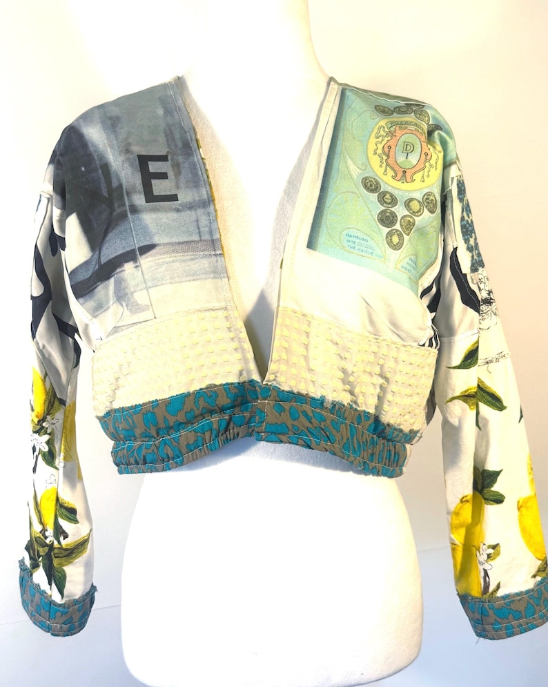 Pode incluir: Casaco curto com um design patchwork &uacute;nico. O casaco apresenta uma mistura de padr&otilde;es, incluindo lim&otilde;es, mapas e estampas abstratas. As mangas t&ecirc;m uma estampa de lim&atilde;o, enquanto o corpo tem um tecido creme texturizado e acabamentos azuis e marrons. A letra "E" &eacute; vis&iacute;vel.
