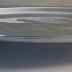 May include: A silver serving tray with a raised rim and three red legs. The tray has a slightly oval shape and a smooth surface.