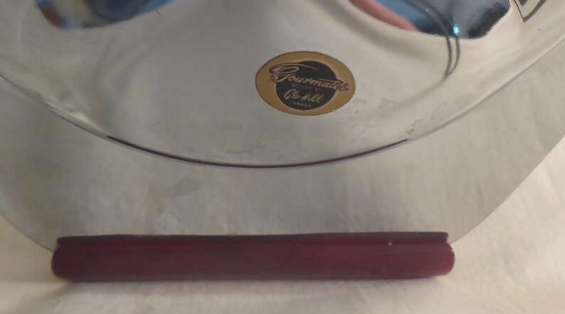 May include: A silver serving tray with a burgundy handle and a gold sticker that reads "Gourmate's, Quality at its best, Canada".