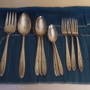 May include: A set of silver-plated silverware in a blue cloth pouch. The set includes forks and spoons.